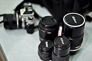 A selection of Nikon camera lenses and a camera on a tabletop, ideal for photography enthusiasts.