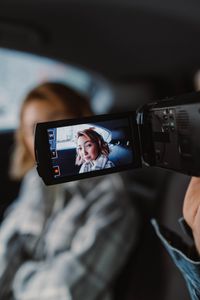 A woman being filmed with a handheld camera inside a car, showcasing a candid moment.