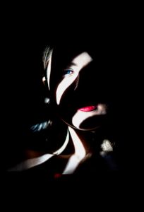 Mysterious portrait of a woman with dramatic lighting and shadow play on her face.